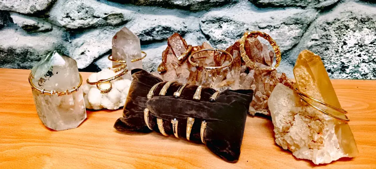 Bracelets dorés ornés de cristaux de quartz, présentés sur un présentoir de velours marron