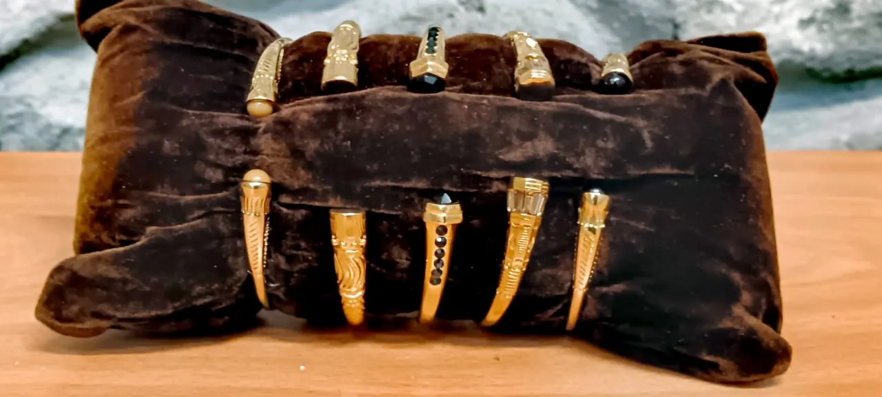 Bracelets dorés à pierres noires, présentés sur un présentoir de velours marron