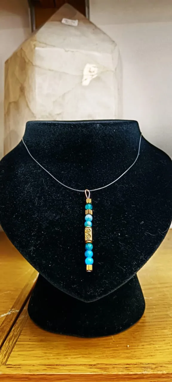 Collier à pendentif de perles turquoise et dorées sur buste en velours noir