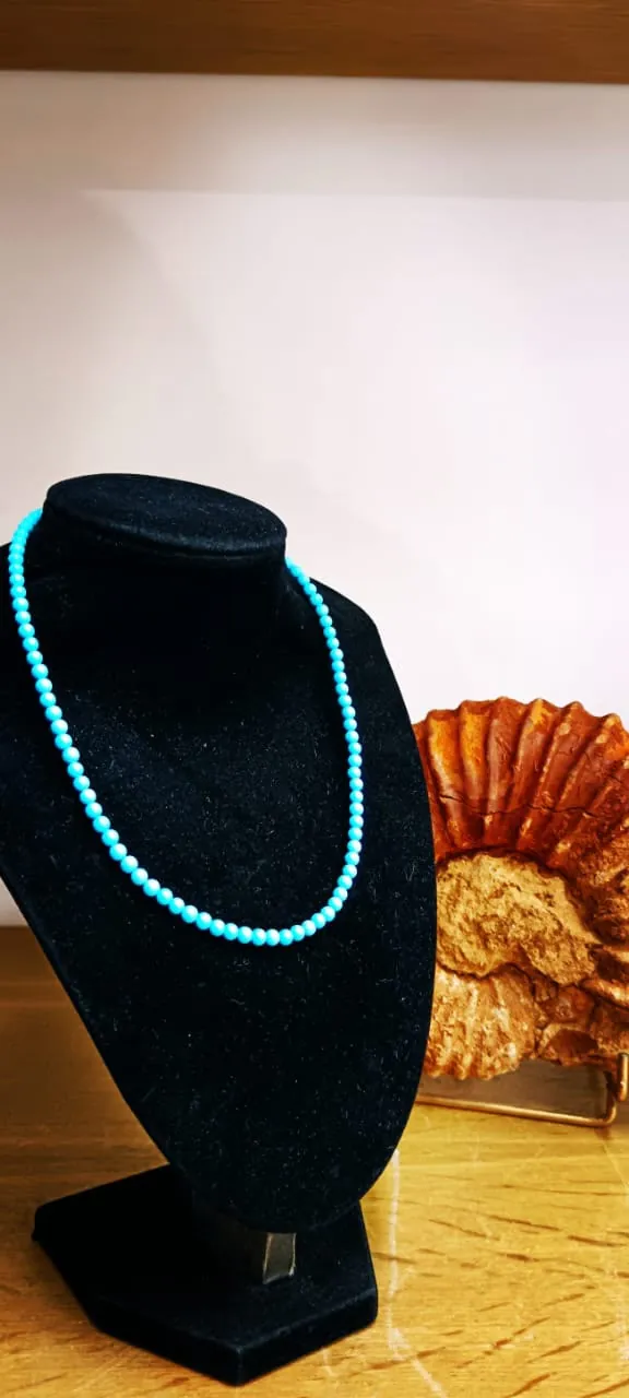 Collier de perles turquoise sur buste en velours noir
