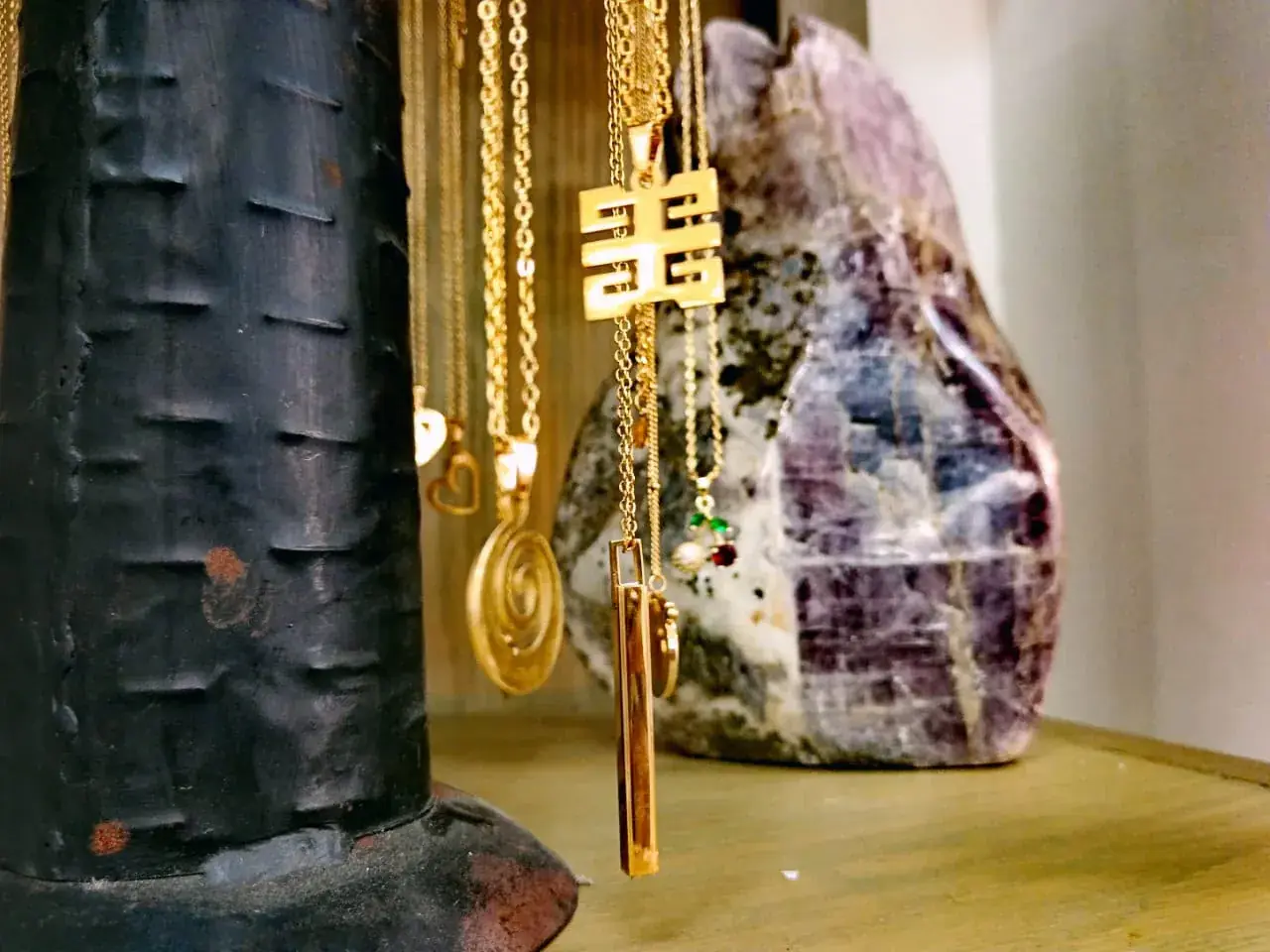 Colliers dorés à pendentifs devant une grosse pierre violette
